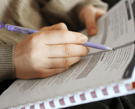A hand writing in a workbook during a psychological testing session.