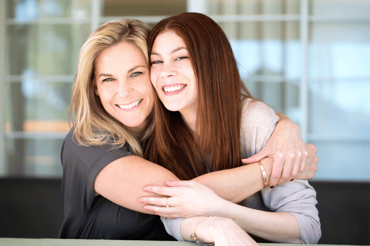 A photo showing a mother embracing her teenage daughter, symbolizing the emotional connection, conflict resolution, and relational healing achieved through family therapy at Lamplight Counseling Services.